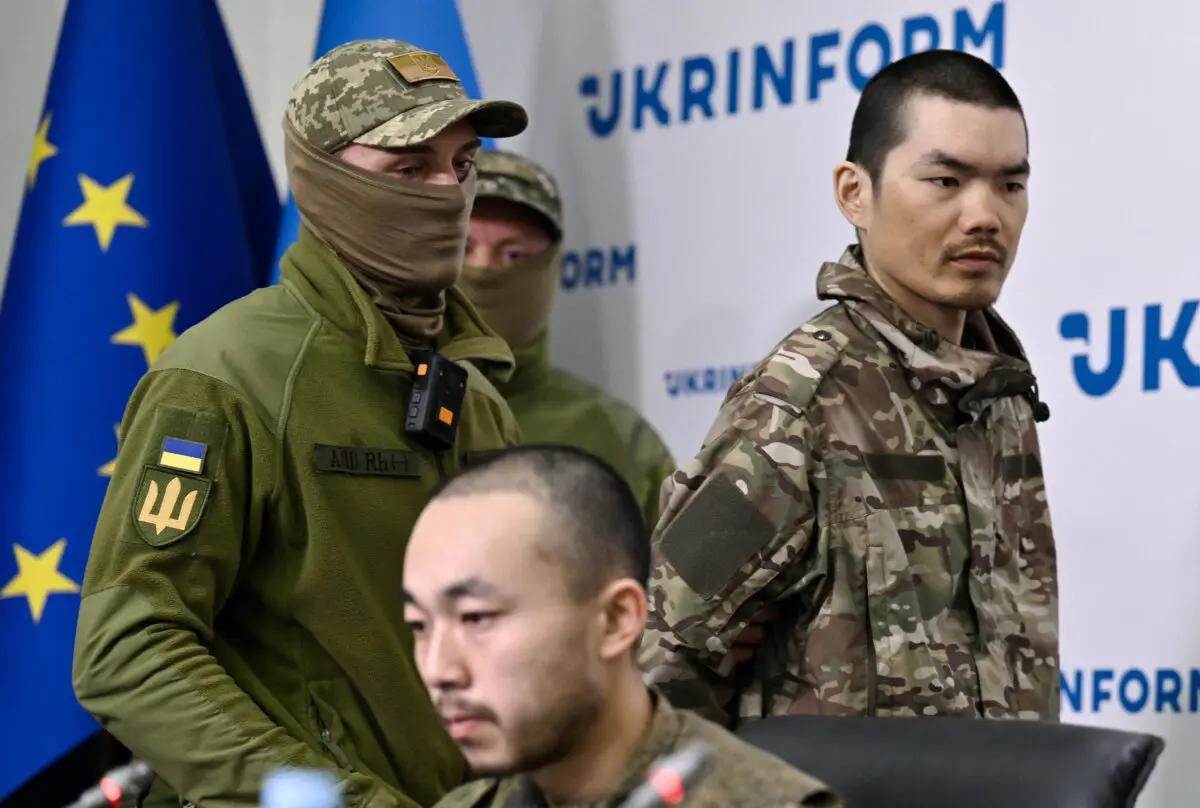 El Servicio de Seguridad de Ucrania escolta al ciudadano chino Wang Guangjung (derecha) a una rueda de prensa con el ciudadano chino Zhang Renbo (centro) en Kiev el 14 de abril de 2025. Los dos ciudadanos chinos fueron capturados por las fuerzas ucranianas en la región de Donetsk. (Genya Savilov/AFP a través de Getty Images)