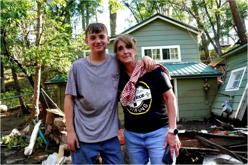 Stephanie Sheffield (d) y su nieto, Matthew, se encuentran frente a su casa, que quedó llena de lodo tras las inundaciones repentinas en el pueblo de Ruidoso, Nuevo México, el 8 de julio de 2025. (Allan Stein/The Epoch Times)