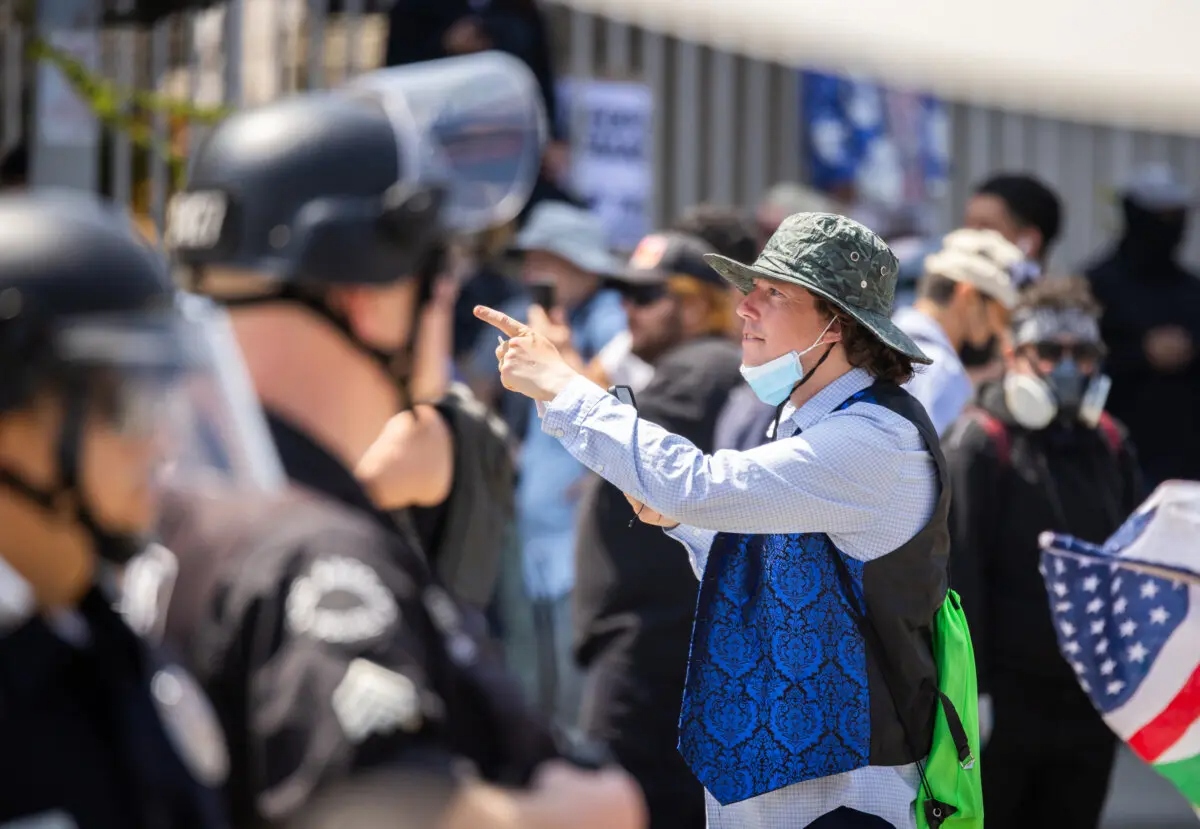 Un manifestante se burla de los oficiales de policía mientras bloquean una calle que conduce a una instalación federal en el centro de Los Ángeles el 9 de junio de 2025. (John Fredricks/The Epoch Times)