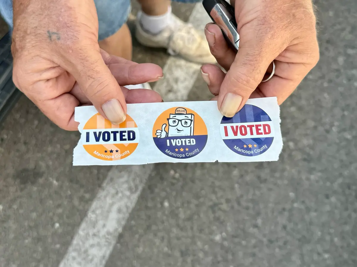 Jerry, un votante del condado de Maricopa, Arizona, muestra sus pegatinas de "Ya voté" después de depositar su voto en el ayuntamiento de Towson el 14 de julio de 2025. (Arjun Singh/The Epoch Times)