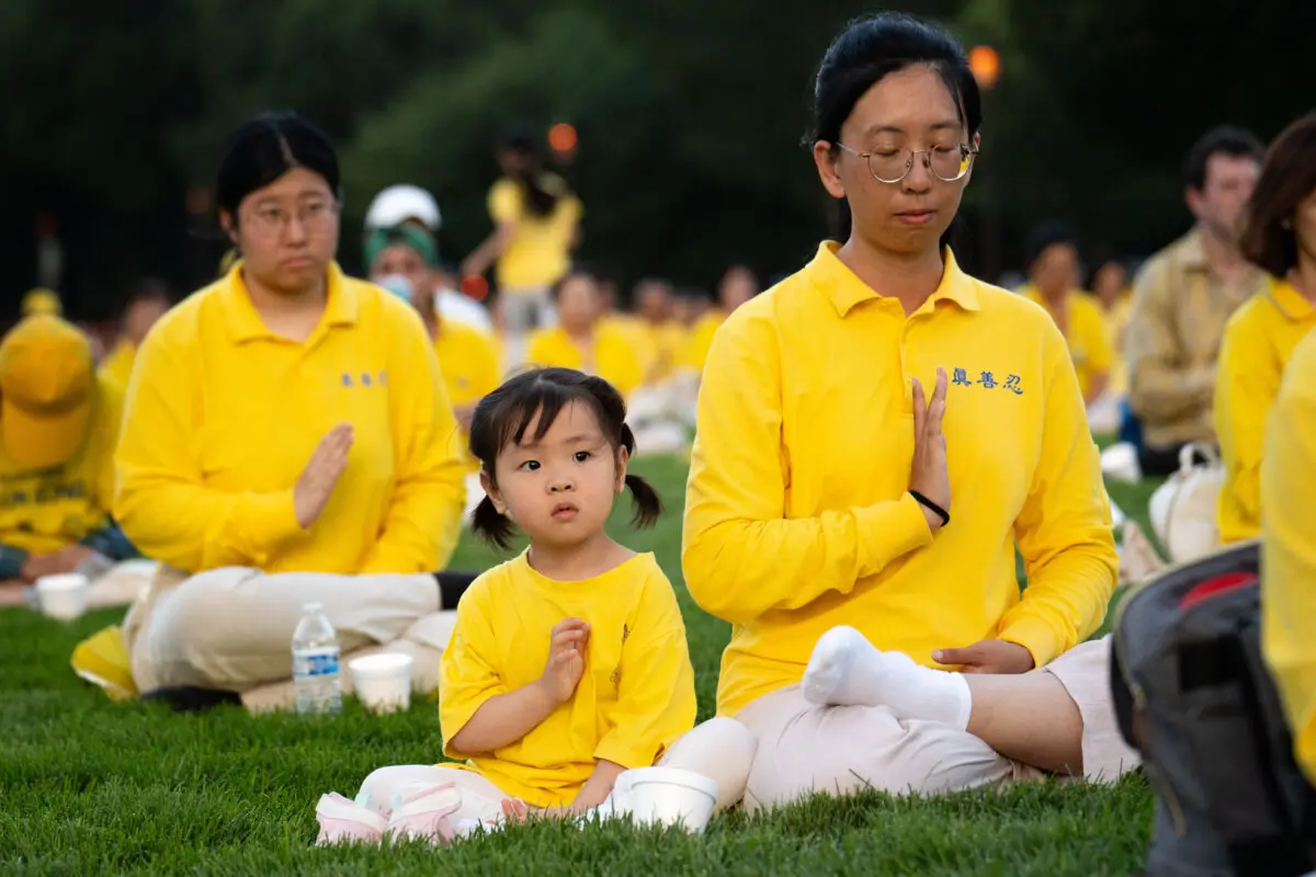 Practicantes de Falun Dafa practican los ejercicios antes de una vigilia con velas en conmemoración de los practicantes de Falun Gong que fueron perseguidos hasta la muerte por el Partido Comunista Chino en China, en Washington, el 17 de julio de 2025. (Samira Bouaou/The Epoch Times)