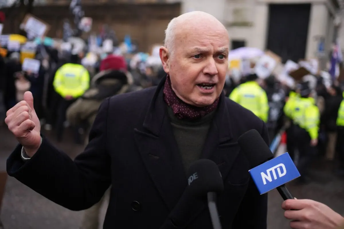 El exlíder del Partido Conservador, Sir Iain Duncan Smith, habla con NTD mientras manifestantes de al menos 28 grupos de la diáspora protestan frente al emplazamiento propuesto para la remodelación de la nueva embajada china en Royal Mint Court, en el centro de Londres, el 8 de febrero de 2025. (Jordan Pettitt/PA Wire).