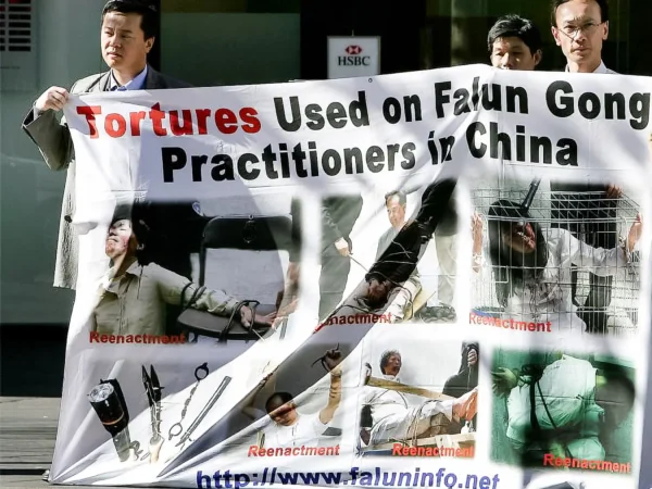 Practicantes de Falun Gong exhiben una pancarta que muestra recreaciones de torturas cerca del barrio chino de Sídney el 20 de julio de 2005. (Greg Wood/AFP/Getty Images)