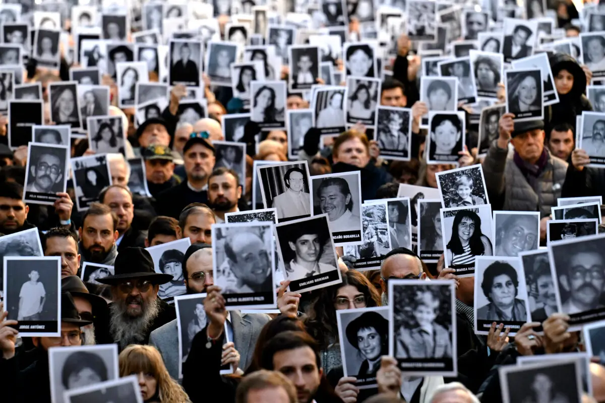 Personas sostienen fotografías de víctimas durante una ceremonia para conmemorar el 31 aniversario del atentado con bomba a la Asociación Mutual Israelita Argentina (AMIA), que dejó 85 muertos y más de 300 heridos, en Buenos Aires, el 18 de julio de 2025. (Luis Robayo/AFP vía Getty Images)