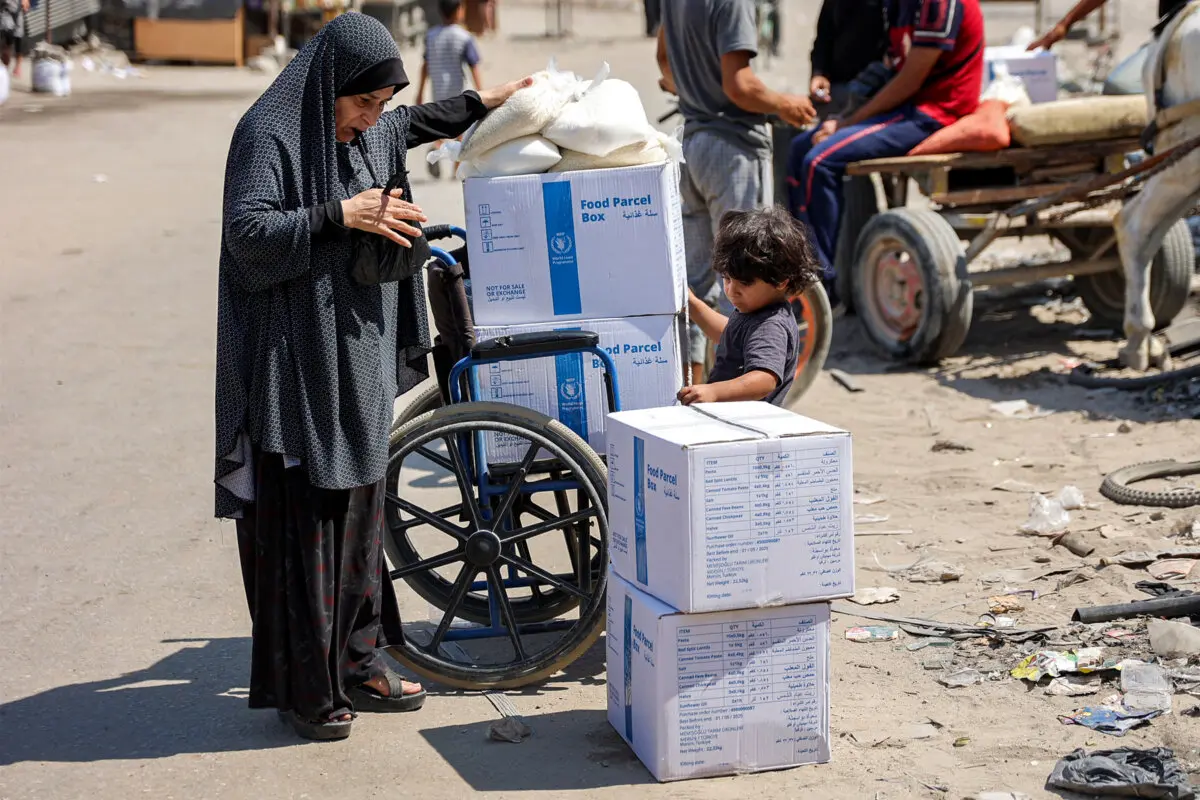 Una mujer y un niño junto a una silla de ruedas cargada con paquetes de ayuda humanitaria en el centro de la ciudad de Gaza, el 27 de agosto de 2024. (Omar Al-Qattaa/AFP a través de Getty Images)