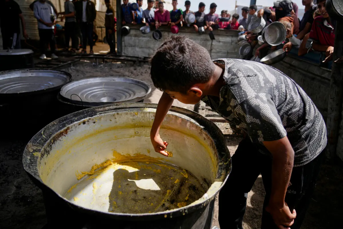 Un niño raspa los restos de una olla vacía después de que se distribuyeran todas las comidas en un comedor comunitario en Khan Younis, en el sur de la Franja de Gaza, el 14 de mayo de 2025. (Abdel Kareem Hana/AP)