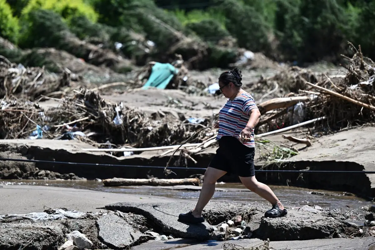 Una mujer camina junto a una zona inundada por las fuertes lluvias de los últimos días en el distrito de Huairou, a las afueras de Beijing, el 30 de julio de 2025. (Pedro Pardo/AFP vía Getty Images)