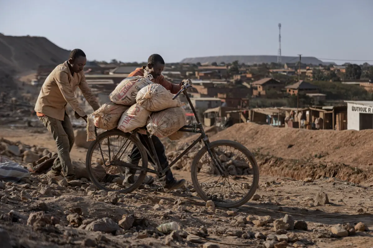 Un padre y su hijo empujan una bicicleta cargada con sacos de cobalto y cobre por un camino de tierra cerca de una mina artesanal en Kolwezi, República Democrática del Congo, el 25 de mayo de 2025. Michel Lunanga/Getty Images