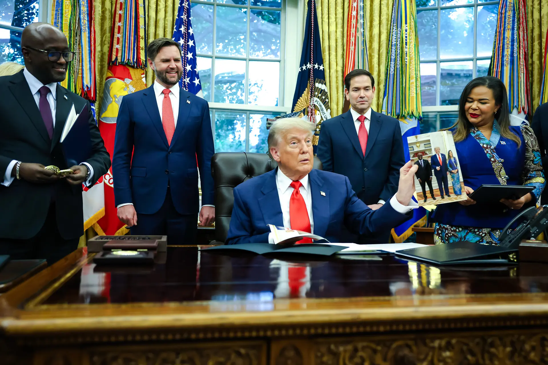 El presidente de Estados Unidos, Donald Trump, sostiene una foto mientras se reúne con el ministro de Asuntos Exteriores y Cooperación de Ruanda, Olivier Nduhungirehe, y la ministra de Asuntos Exteriores de la República Democrática del Congo, Thérèse Kayikwamba Wagner, en el Despacho Oval el 27 de junio de 2025. La reunión se celebró tras un acuerdo de paz negociado por la Casa Blanca y firmado por funcionarios de ambos países para poner fin al conflicto en el este del Congo. La administración busca utilizar incentivos económicos para ayudar a fomentar la estabilidad regional. (Joe Raedle/Getty Images)