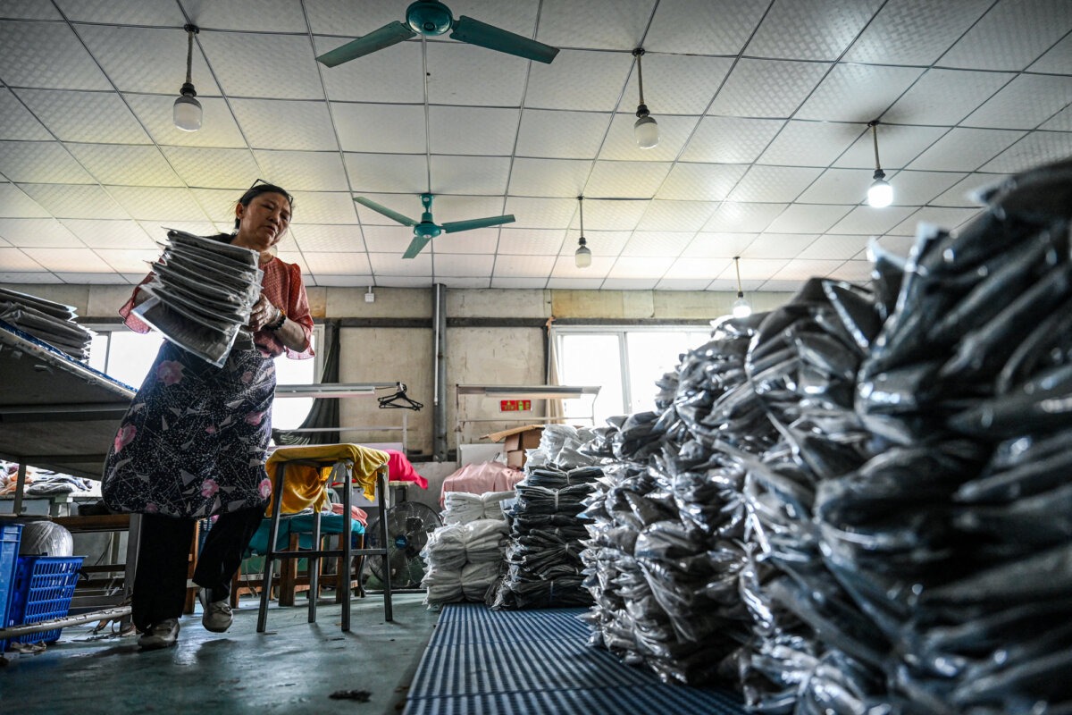 Una empleada clasifica prendas para las plataformas de comercio electrónico chinas Temu en una fábrica de ropa en Guangzhou, provincia de Guangdong, China, el 16 de abril de 2025. Algunos trabajadores chinos han publicado en las redes sociales quejas sobre su despido temporal. (Jade Gao/AFP a través de Getty Images).