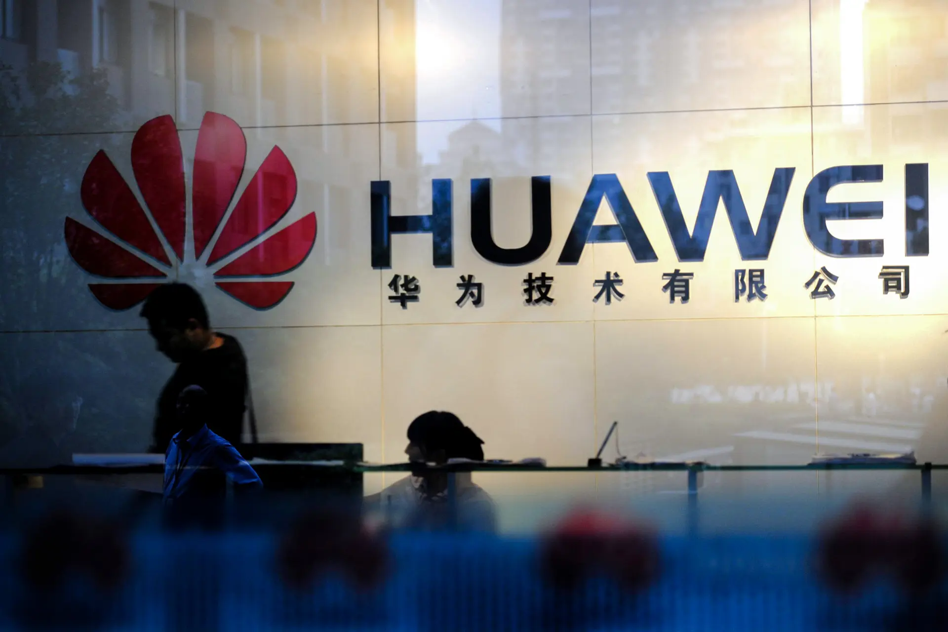 Personal y visitantes pasan por el vestíbulo de la oficina de Huawei en Wuhan, provincia de Hubei, China, el 8 de octubre de 2012. A principios de la década de 2000, legisladores, funcionarios y expertos de todo el mundo expresaron su preocupación por la seguridad nacional de los servicios de telecomunicaciones chinos, incluido Huawei.( STR/AFP/GettyImages)
