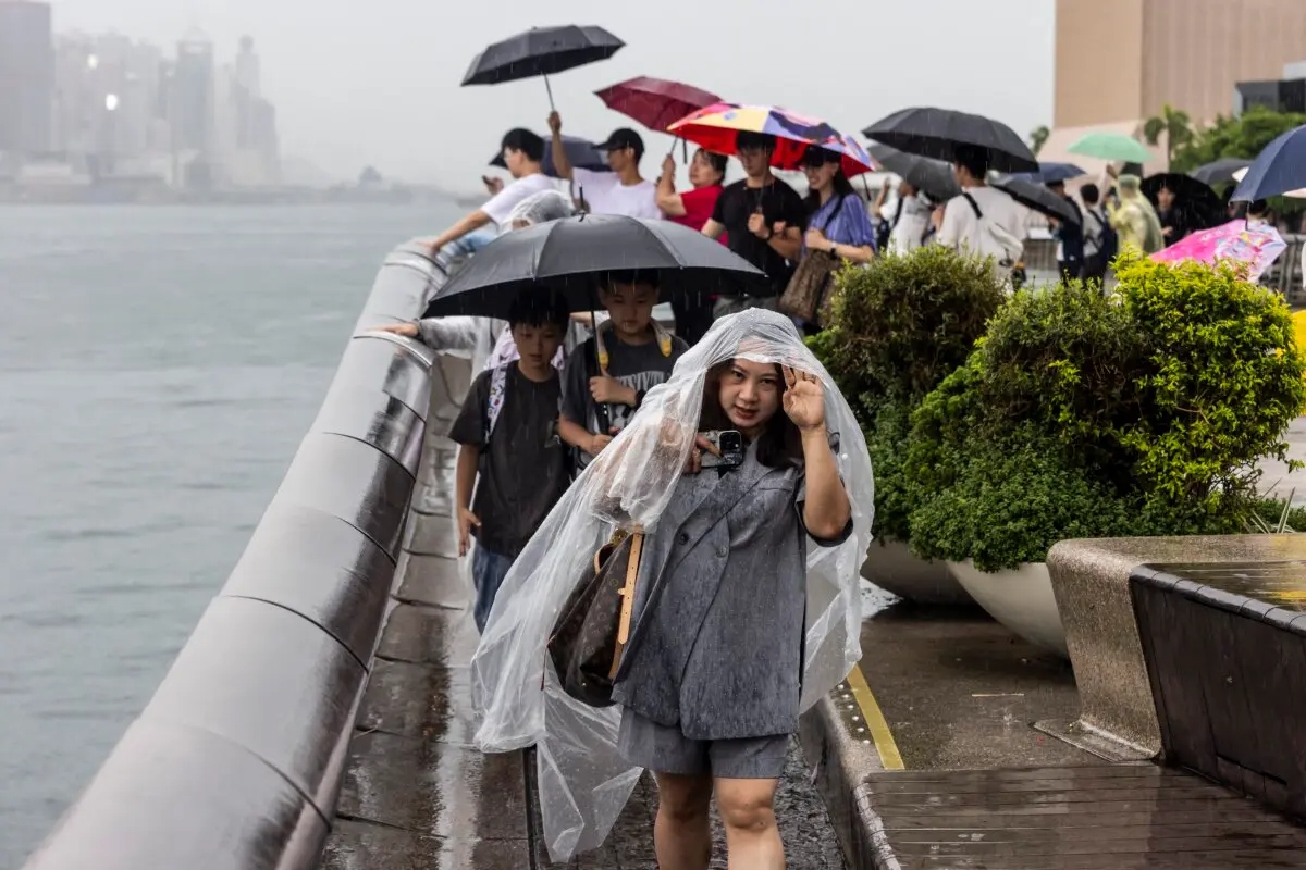 La gente utiliza paraguas para protegerse de la lluvia en Hong Kong el 14 de agosto de 2025, mientras el tifón Podul se debilita y se convierte en una tormenta tropical severa. (Isaac Lawrence /AFP a través de Getty Images)