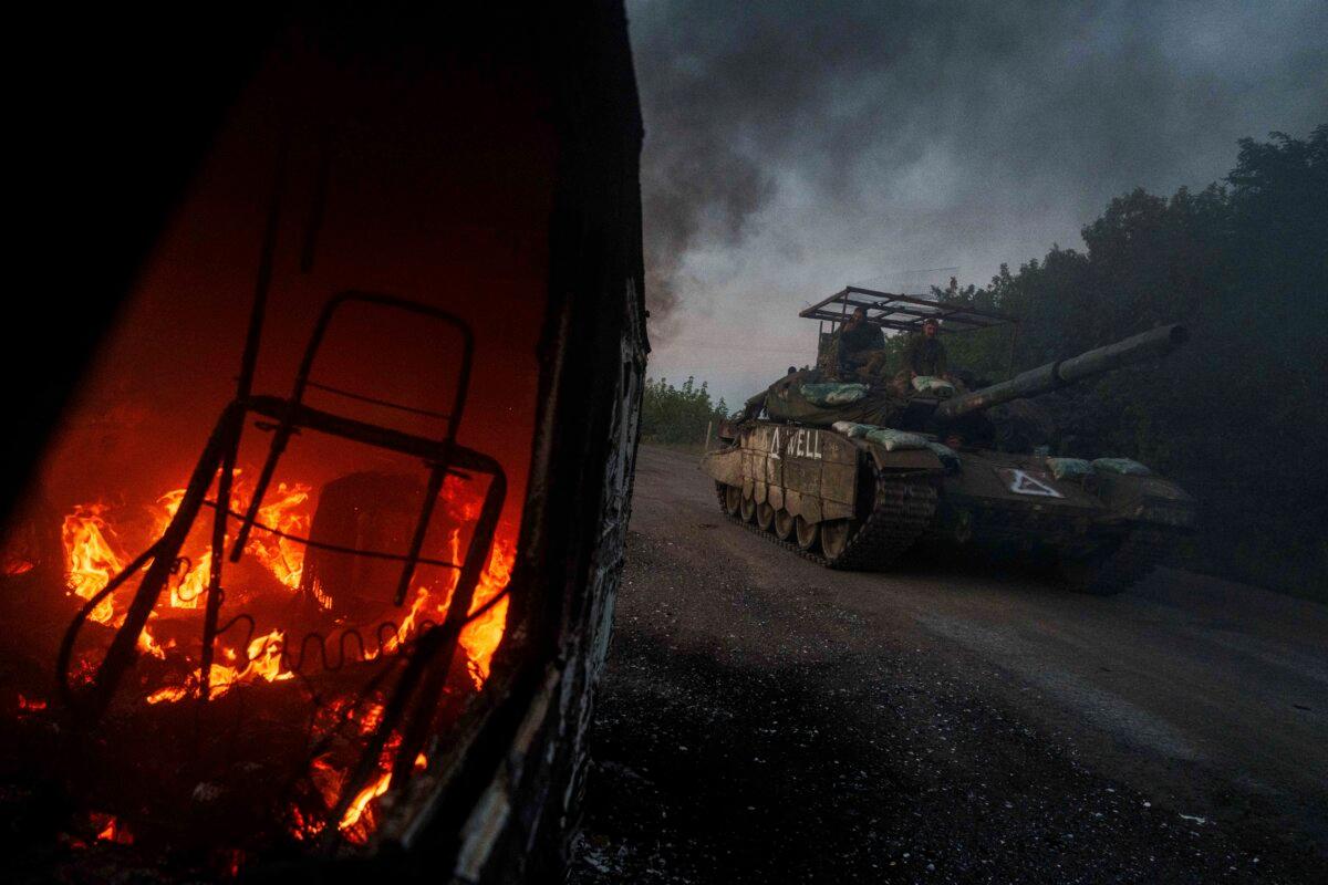 Un tanque ucraniano pasa junto a un auto en llamas en la región de Sumy, cerca de la frontera entre Rusia y Ucrania, el 14 de agosto de 2024. (AP Photo/Evgeniy Maloletka).