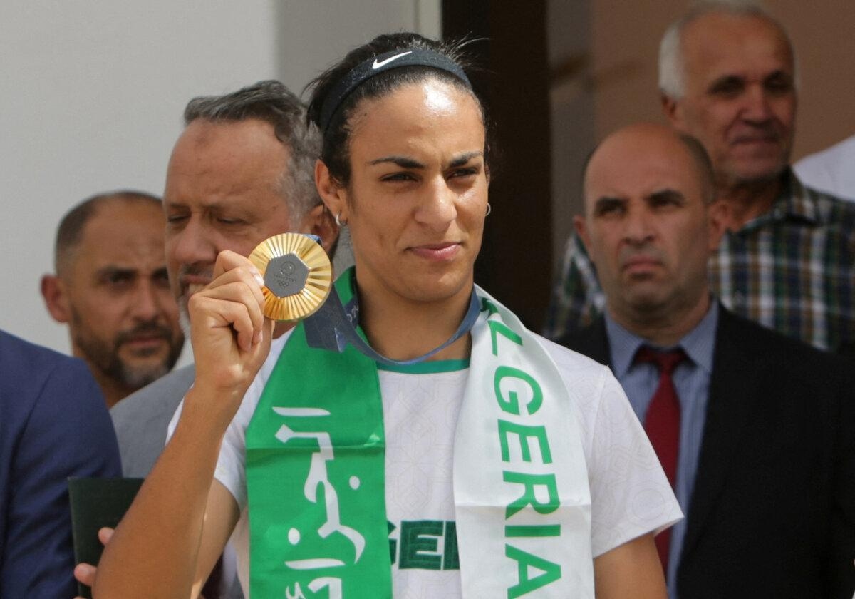 La boxeadora argelina Imane Khelif, que ganó la medalla de oro en boxeo femenino de peso welter en los Juegos Olímpicos, sostiene una medalla a su llegada al aeropuerto de Argel, Argelia, el 12 de agosto de 2024. (Ramzi Boudina/Reuters)