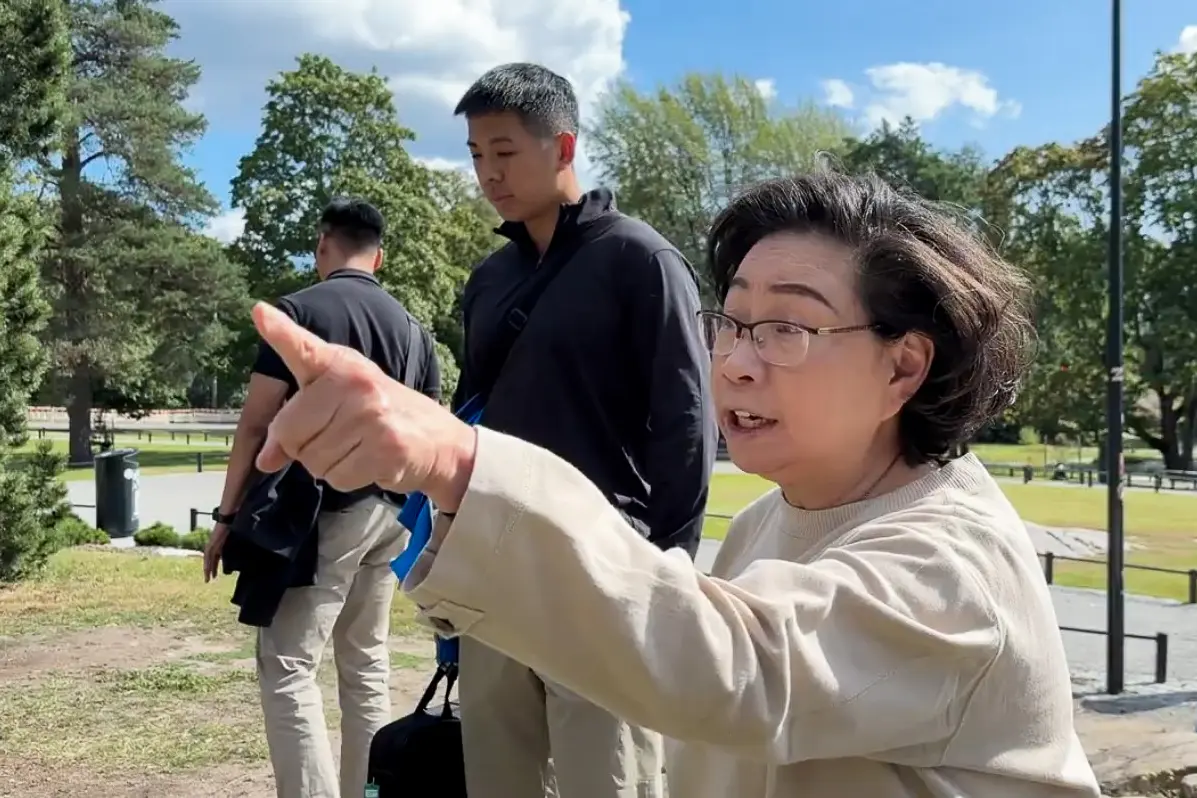 Regina Leung Tong Ching-yee, esposa del exjefe ejecutivo de Hong Kong, Leung Chun-ying, en un intercambio conflictivo con practicantes de Falun Gong en el parque Sibelius, Helsinki, el 13 de agosto de 2025. (Cortesía de los practicantes de Falun Gong de Helsinki).