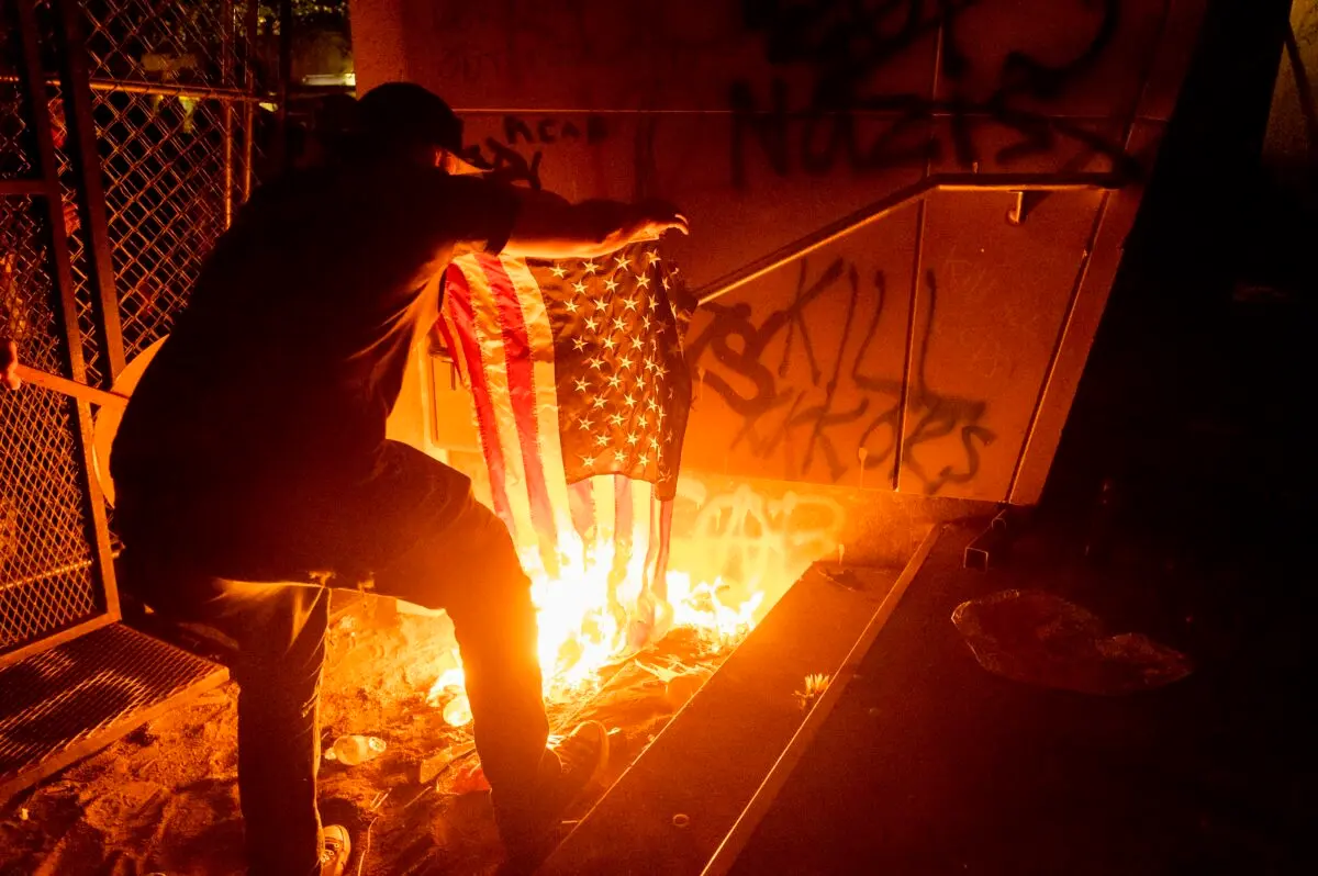 Un manifestante quema una bandera estadounidense frente al juzgado federal Mark O. Hatfield en Portland, Oregón, el 20 de julio de 2020. (Noah Berger/AP Photo).