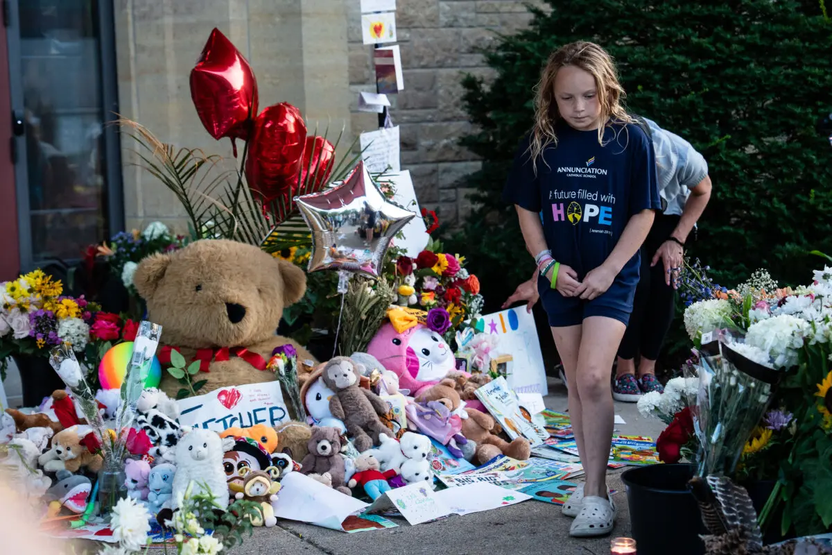 En señal de respeto a los dos escolares que murieron en un tiroteo, los dolientes visitan un memorial improvisado en la iglesia católica Annunciation en Minneapolis el 28 de agosto de 2025. (Madalina Kilroy/The Epoch Times)