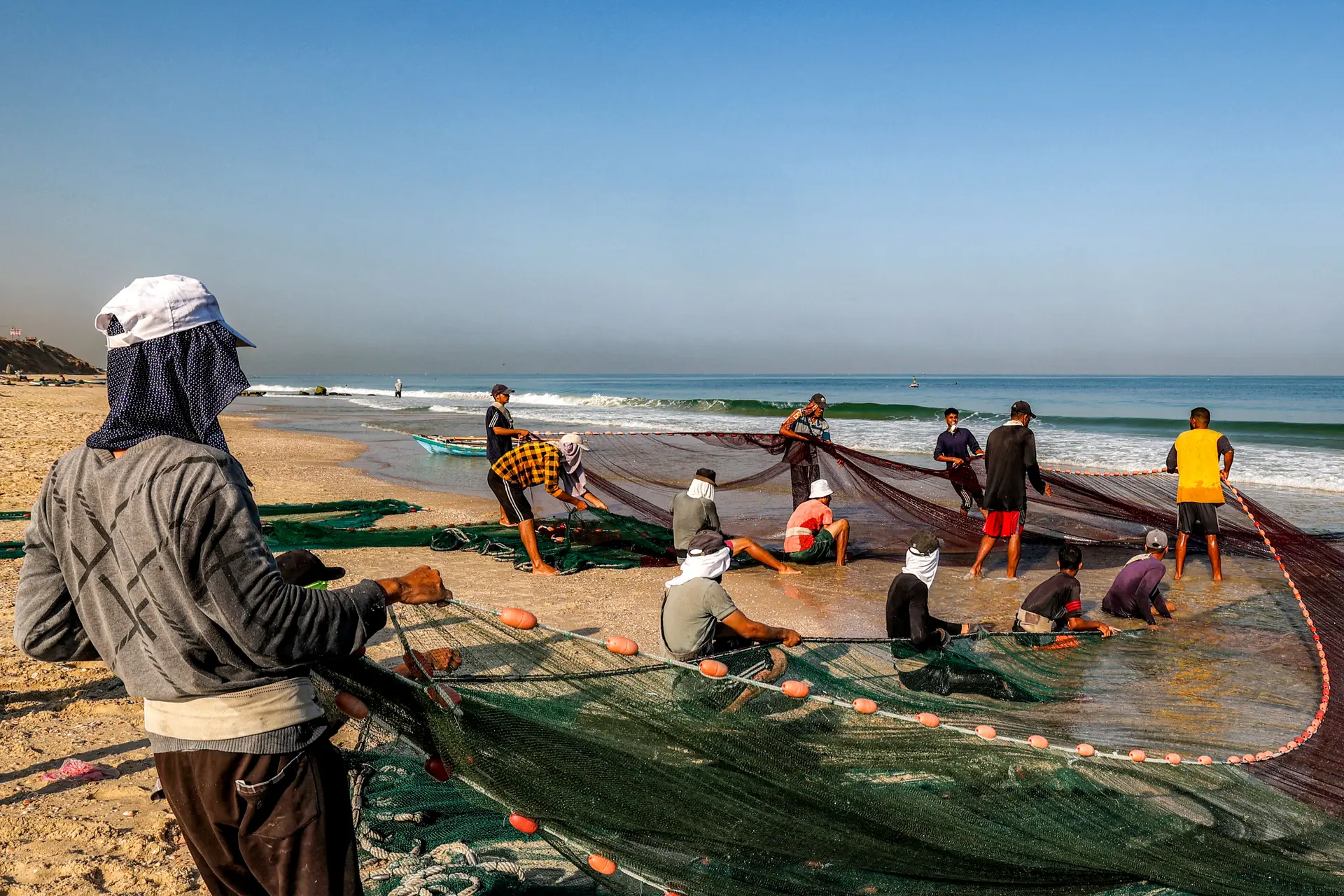 Los pescadores tiran de sus redes para recuperar su pesca en una playa del campamento de Nuseirat para refugiados palestinos, en el centro de la Franja de Gaza, el 30 de agosto de 2025. (Eyad Baba/AFP vía Getty Images)