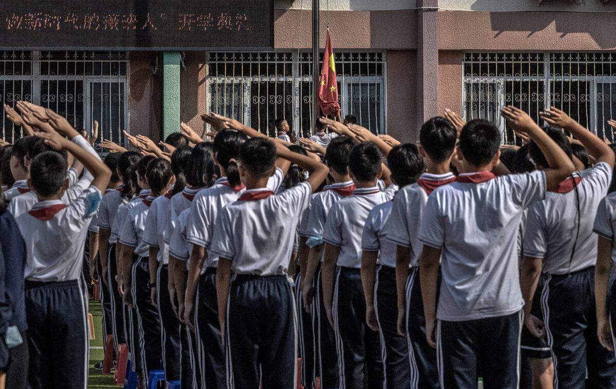 Estudiantes saludan mientras se iza la bandera nacional en una escuela primaria de Beijing el 1 de septiembre de 2021. (Kevin Frayer/Getty Images)