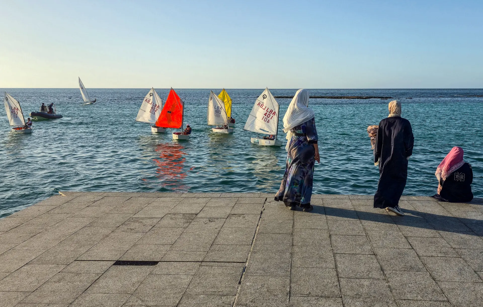 Mujeres observan a miembros de un club náutico durante sus prácticas cerca de la cornisa costera de Trípoli, Libia, el 1 de septiembre de 2025. (Mahmud Turkia/AFP vía Getty Images)