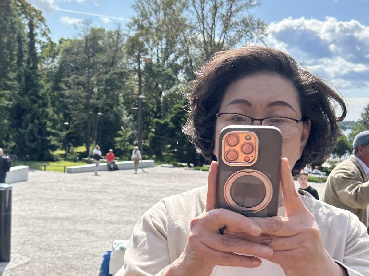 Regina Leung Tong Ching-yee, esposa de Leung Chun-ying, fotografía a practicantes de Falun Gong en el lugar de meditación en Helsinki, Finlandia, el 13 de agosto de 2025.( Cortesía del Centro de Información de Falun Dafa).