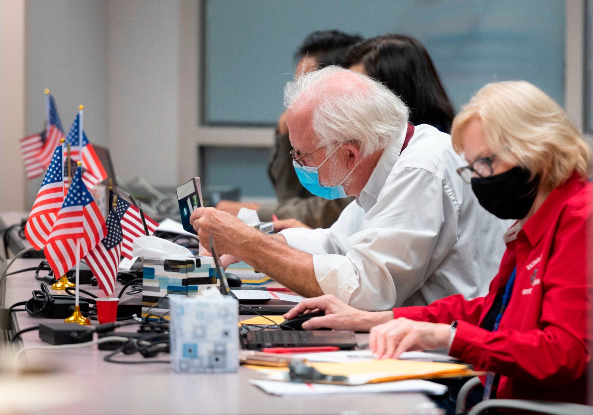 Un hombre comprueba la identificación de un votante antes de entregarle una papeleta en un centro de votación anticipada en Fairfax, Virginia, el 18 de septiembre de 2020. (ANDREW CABALLERO-REYNOLDS/AFP a través de Getty Images).