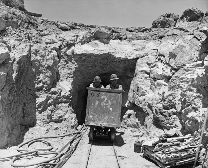 Dos mineros empujan un carro de mineral al salir de una mina de uranio en California, alrededor de 1955. (Tom Stimson/FPG/Archive Photos/Getty Images)