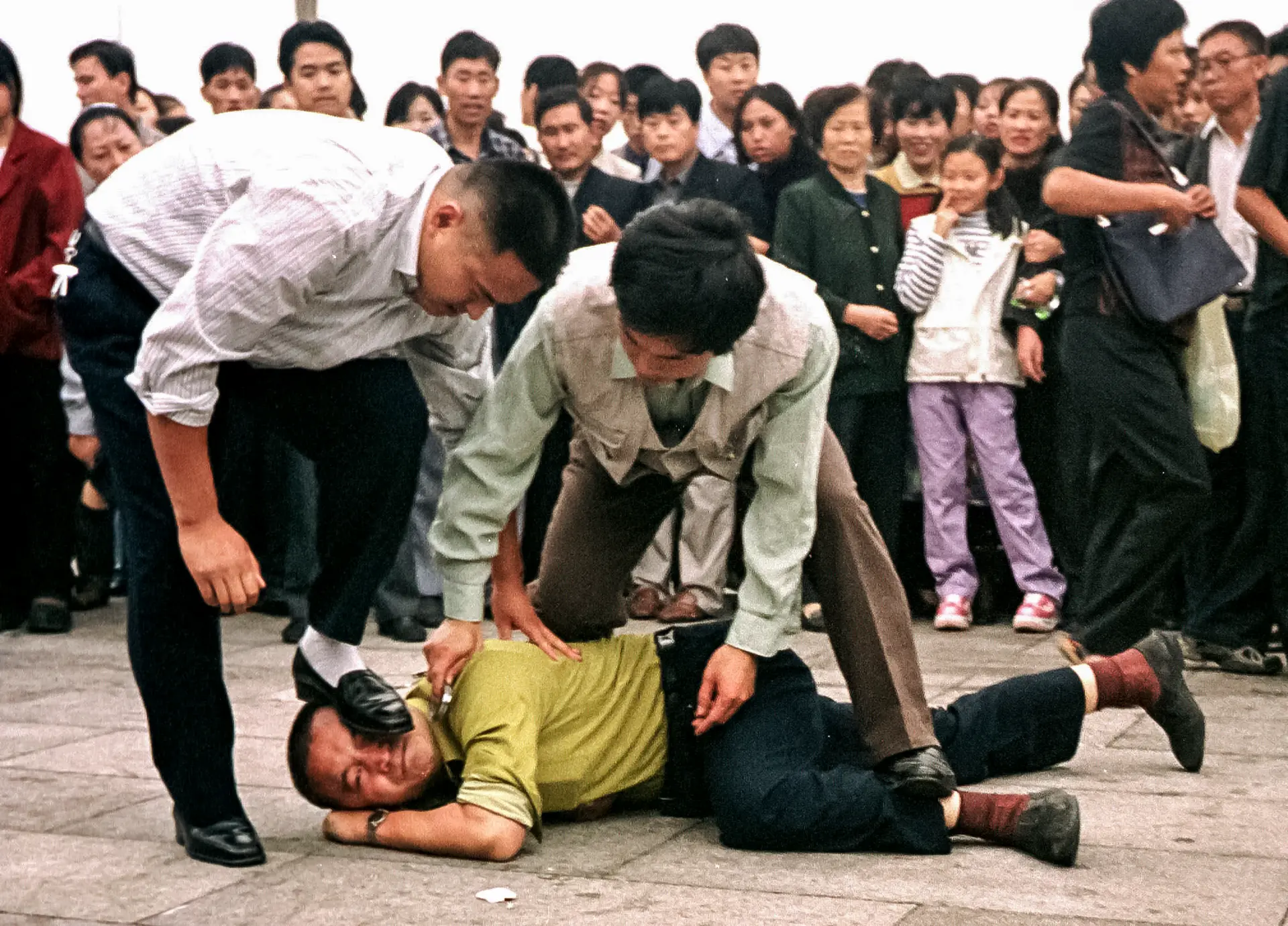 La policía detiene a un practicante de Falun Gong mientras una multitud se reúne a su alrededor en la plaza de Tiananmen, en Beijing, el 1 de octubre de 2000. (Chien-Min Chung/AP Photo)