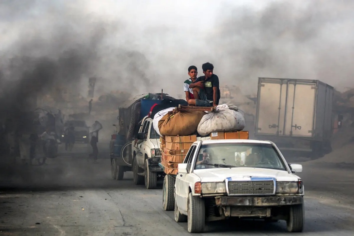 Jóvenes viajan sobre paquetes y muebles en una plataforma remolcada por un vehículo mientras la gente evacúa hacia el sur desde la ciudad de Gaza, el 2 de septiembre de 2025. (Eyad Baba/AFP a través de Getty Images)