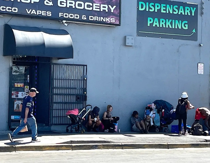 Un grupo de personas se sienta a la sombra de un edificio junto a Central Avenue, en el Distrito Internacional de Albuquerque, Nuevo México, el 3 de septiembre de 2025. (Allan Stein/The Epoch Times)