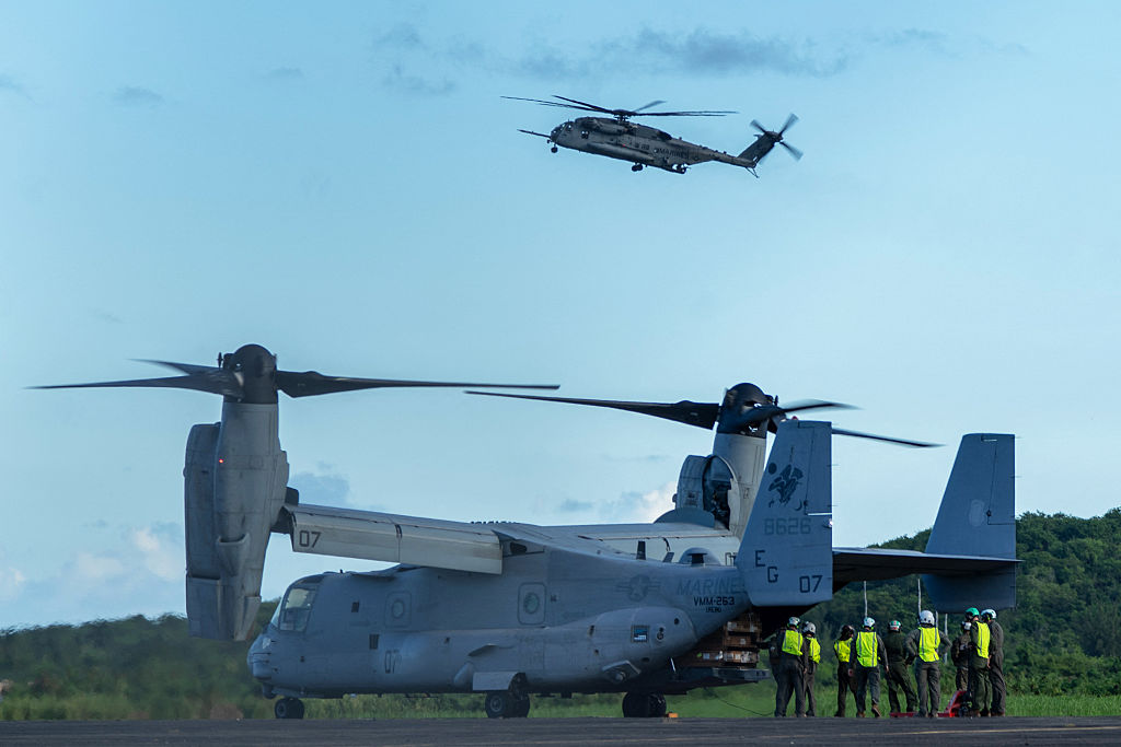 Infantes de Marina de los EE. UU. descargan equipo de un V-22 Osprey mientras un helicóptero Sikorsky CH-53K King Stallion sobrevuela a su llegada al Aeropuerto José Aponte de la Torre, antigua Estación Naval Roosevelt Roads, en Ceiba, Puerto Rico, el 1 de septiembre de 2025. (JAYDEE LEE SERRANO/AFP vía Getty Images)