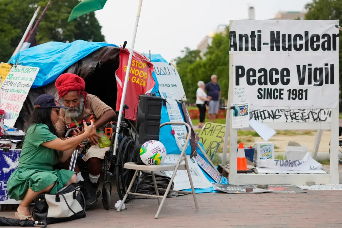 Philipos Melaku-Bello (2.º por la izquierda) mira el teléfono de un transeúnte durante la vigilia por la paz en el parque Lafayette, frente a la Casa Blanca, en Washington, el 5 de septiembre de 2025. (Pablo Martínez Monsiváis/AP Photo)