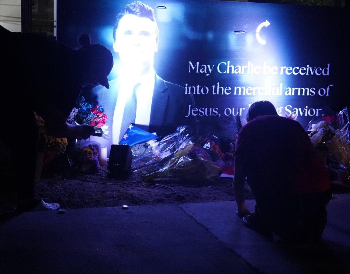 Los simpatizantes depositan flores a los pies de una pancarta iluminada en memoria del fundador de Turning Point USA, Charlie Kirk, asesinado en Phoenix, Arizona, el 10 de septiembre de 2025. (Allan Stein/The Epoch Times)