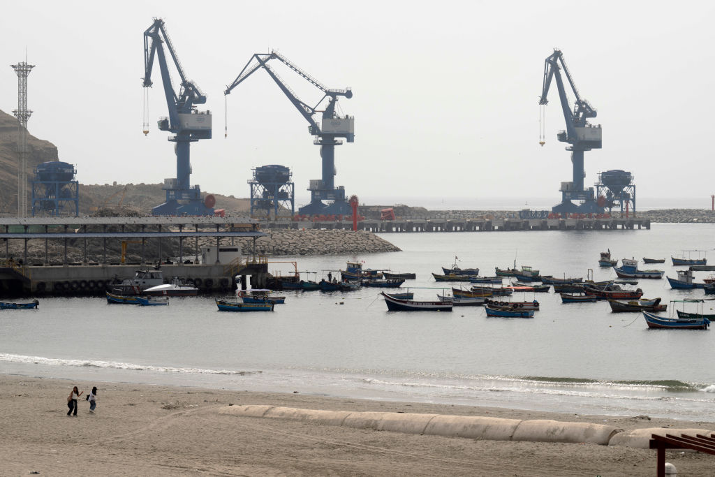 Grúas del megapuerto de Chancay se ven desde el puerto de la ciudad, donde descansan embarcaciones pesqueras tradicionales, a 78 kilómetros al norte de Lima, la capital peruana, el 29 de octubre de 2024. Estaba prevista su inauguración el 14 de noviembre de 2024 por la presidente de Perú Dina Boluarte y el líder chino Xi Jinping, en el marco de la cumbre de Cooperación Económica Asia-Pacífico (APEC) en Lima. (Foto de CRIS BOURONCLE/AFP vía Getty Images)