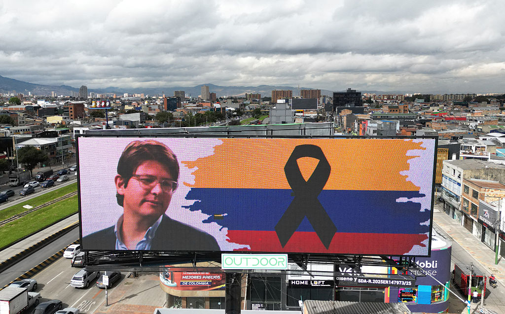 Vista aérea de un anuncio con la imagen del candidato presidencial colombiano asesinado Miguel Uribe y una bandera colombiana con un lazo negro en Bogotá el 12 de agosto de 2025. El candidato presidencial colombiano Miguel Uribe murió dos meses después de recibir un disparo en la cabeza durante un acto de campaña, según anunció su esposa la madrugada del 11 de agosto de 2025. El ataque reavivó los temores de un retorno al pasado violento del país. (Foto de Raul Arboleda/AFP vía Getty Images)