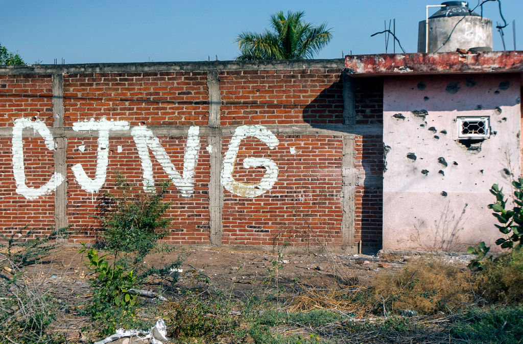 Vista de un muro, perforado por impactos de bala, donde se ven las iniciales del grupo criminal Cartel Jalisco Nueva Generación (CJNG) a la entrada de la comunidad de Aguililla, en Michoacán, México, el 23 de abril de 2021. (ENRIQUE CASTRO/AFP vía Getty Images)