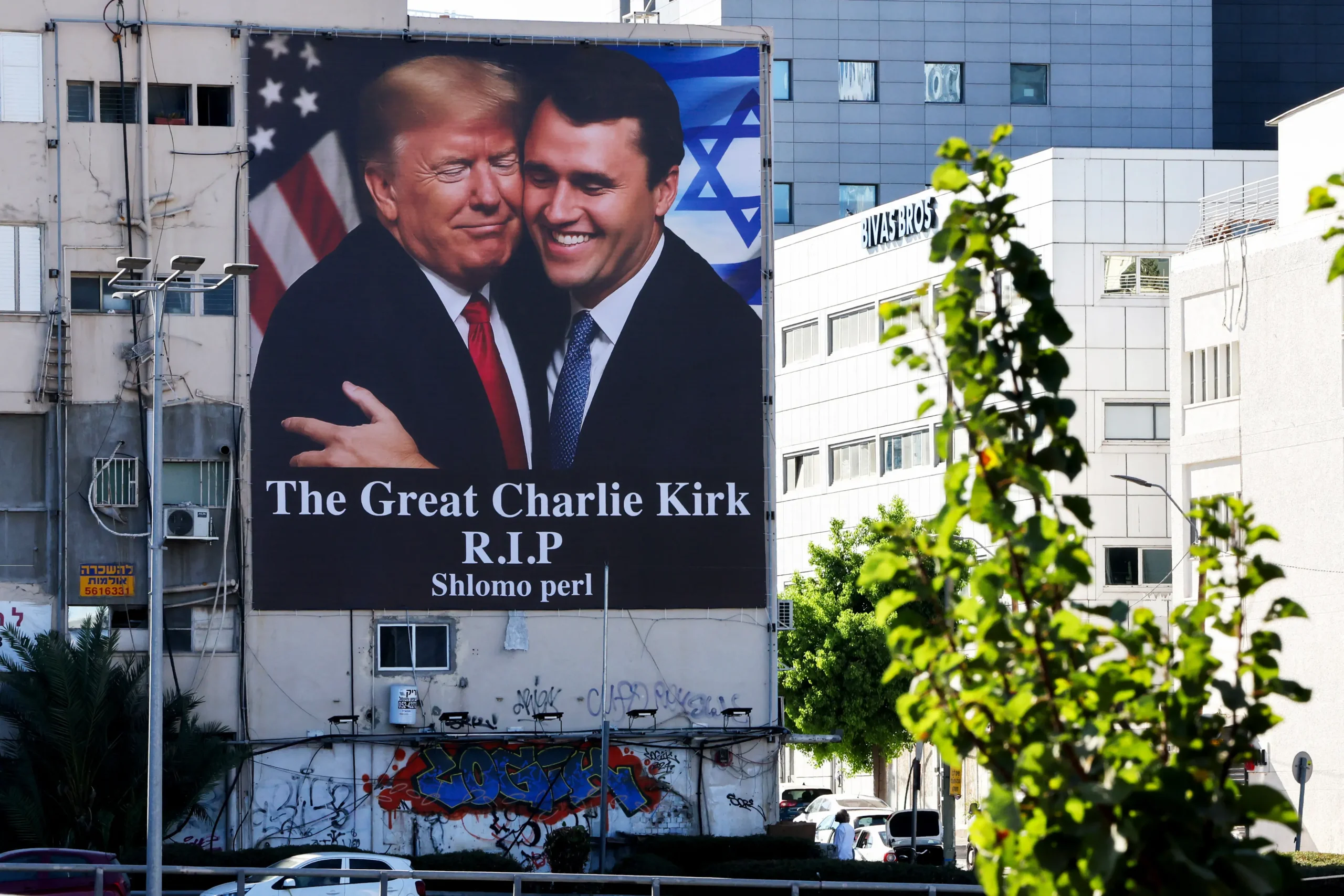 <em>Una valla publicitaria con la imagen del presidente de Estados Unidos, Donald Trump, abrazando al destacado influencer conservador Charlie Kirk, que impactado y asesinado por una sola bala mientras hablaba frente a una gran multitud en la Universidad del Valle de Utah, en la ciudad de Orem, el 10 de septiembre, cuelga en el lateral de un edificio en Tel Aviv, el 13 de septiembre de 2025. Jack Guez/AFP vía Getty Images</em>