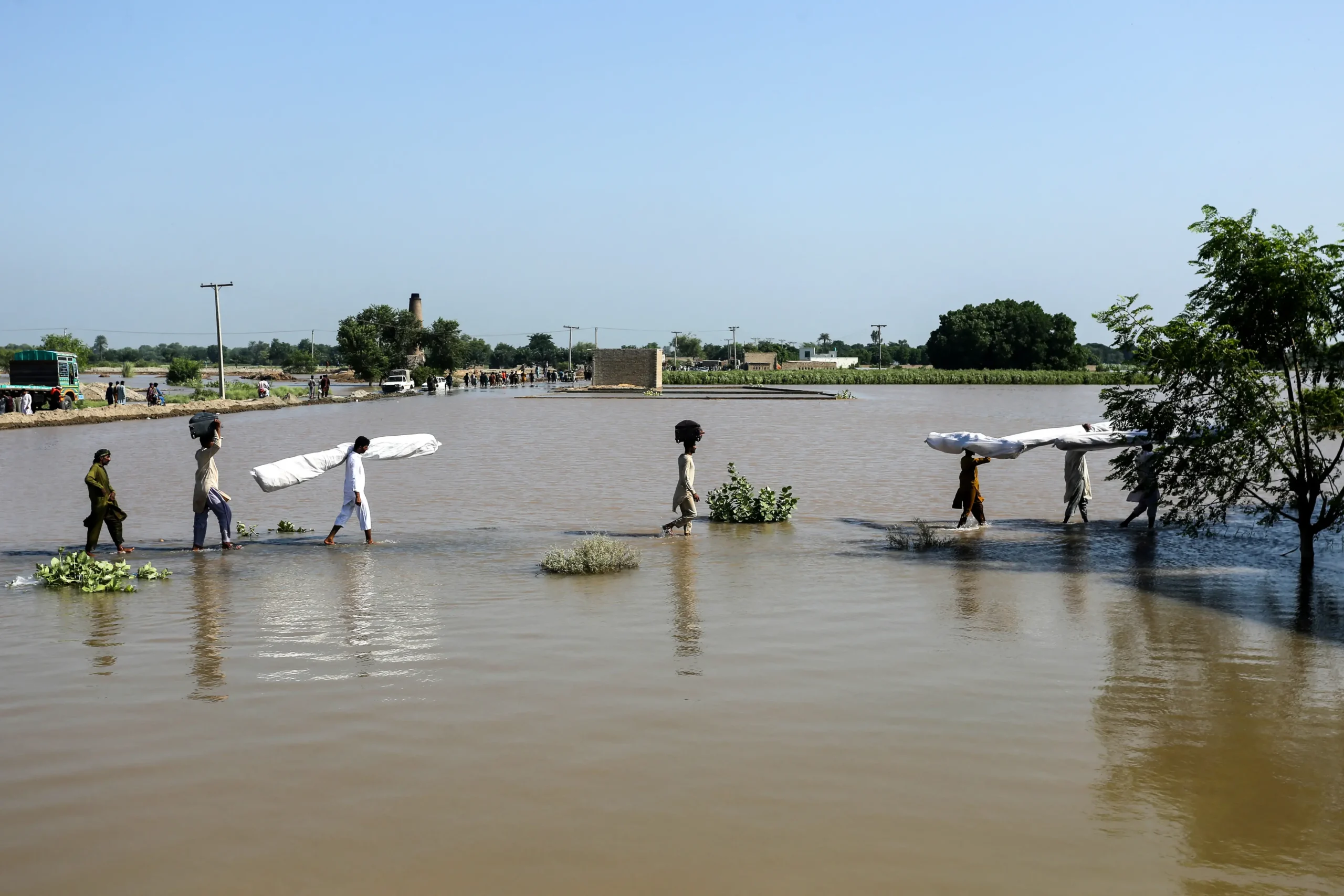 <em>Personas afectadas por las inundaciones llevan carpas improvisadas mientras atraviesan las aguas en Alipur, en el distrito de Muzaffargarh de la provincia de Punyab, Pakistán, el 13 de septiembre de 2025. Shahid Saeed Mirza/AFP vía Getty Images</em>