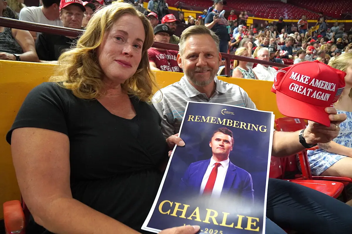 Denise y Bob Ruchala, de Litchfield Park, Arizona, sostienen una foto del líder juvenil conservador asesinado Charlie Kirk y una gorra de "Make America Great Again" durante una vigilia en Tempe, Arizona, el 15 de septiembre de 2025. (Allan Stein/The Epoch Times).