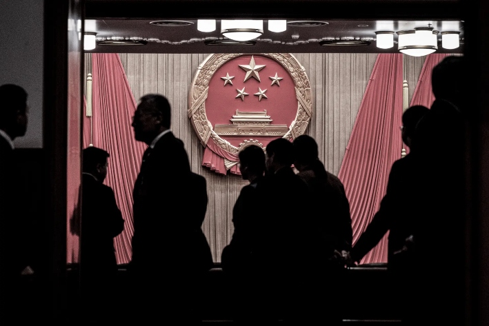 Un emblema nacional se ve mientras los delegados y los agentes de seguridad se reúnen a la entrada del auditorio antes de la sesión de clausura de la Asamblea Popular Nacional en el Gran Salón del Pueblo en Beijing, el 11 de marzo de 2024. (Kevin Frayer/Getty Images)