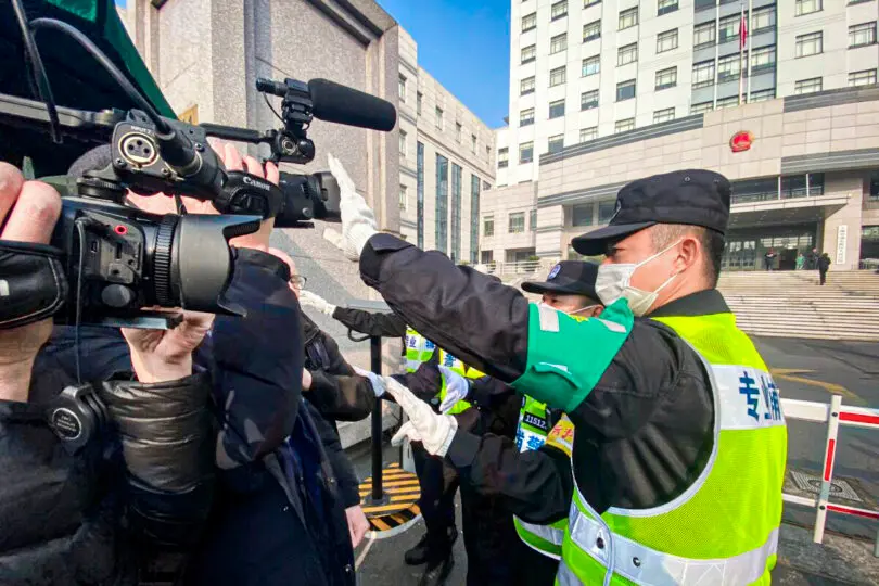 Un policía cubre una cámara para impedir que los periodistas graben imágenes fuera del Tribunal Popular del Nuevo Distrito de Pudong de Shanghái, donde la periodista ciudadana china Zhang Zhan será juzgada en Shanghái, el 28 de diciembre de 2020. (Leo Ramírez/AFP a través de Getty Images)