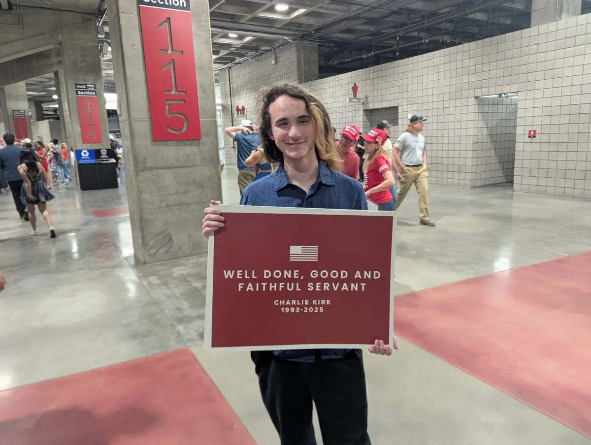 David Watz sostiene un cartel con el lema "Bien hecho, siervo bueno y fiel" en el funeral de Charlie Kirk en el State Farm Stadium de Phoenix, Arizona, el 21 de septiembre de 2025. (Ryan Morgan/The Epoch Times)