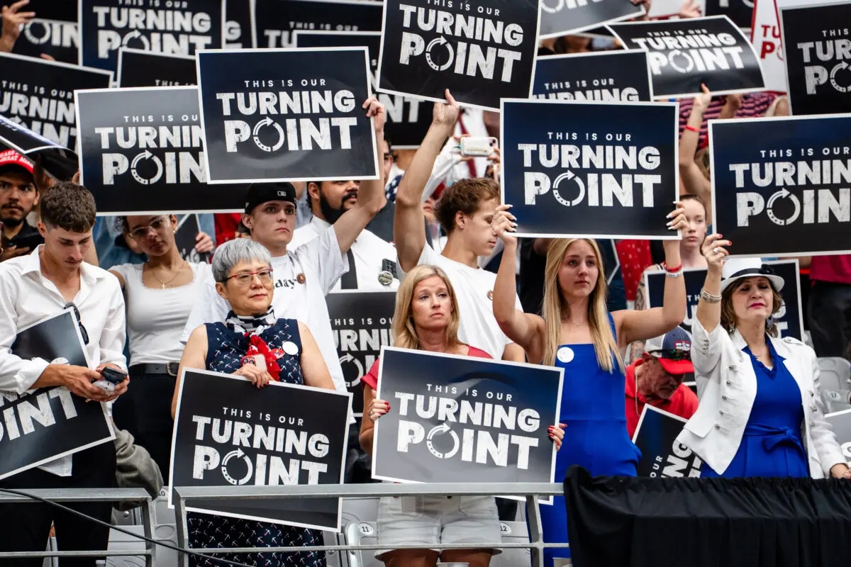 La gente sostiene carteles mientras participa en el evento "Construyendo un legado: Recordando a Charlie Kirk" en el estadio State Farm de Glendale, Arizona, el 21 de septiembre de 2025. (Madalina Kilroy/The Epoch Times)