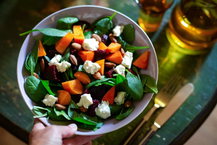 Un bol de ensalada de espinacas con kaki, remolacha, almendras y queso gorgonzola. El folato, o vitamina B9, se obtiene de alimentos como las espinacas y los frutos secos. Las autoridades afirmaron que la leucovorina, o ácido folínico recetado, puede ayudar a las personas autistas con sus síntomas. (Kathrin Ziegler/Getty Images)