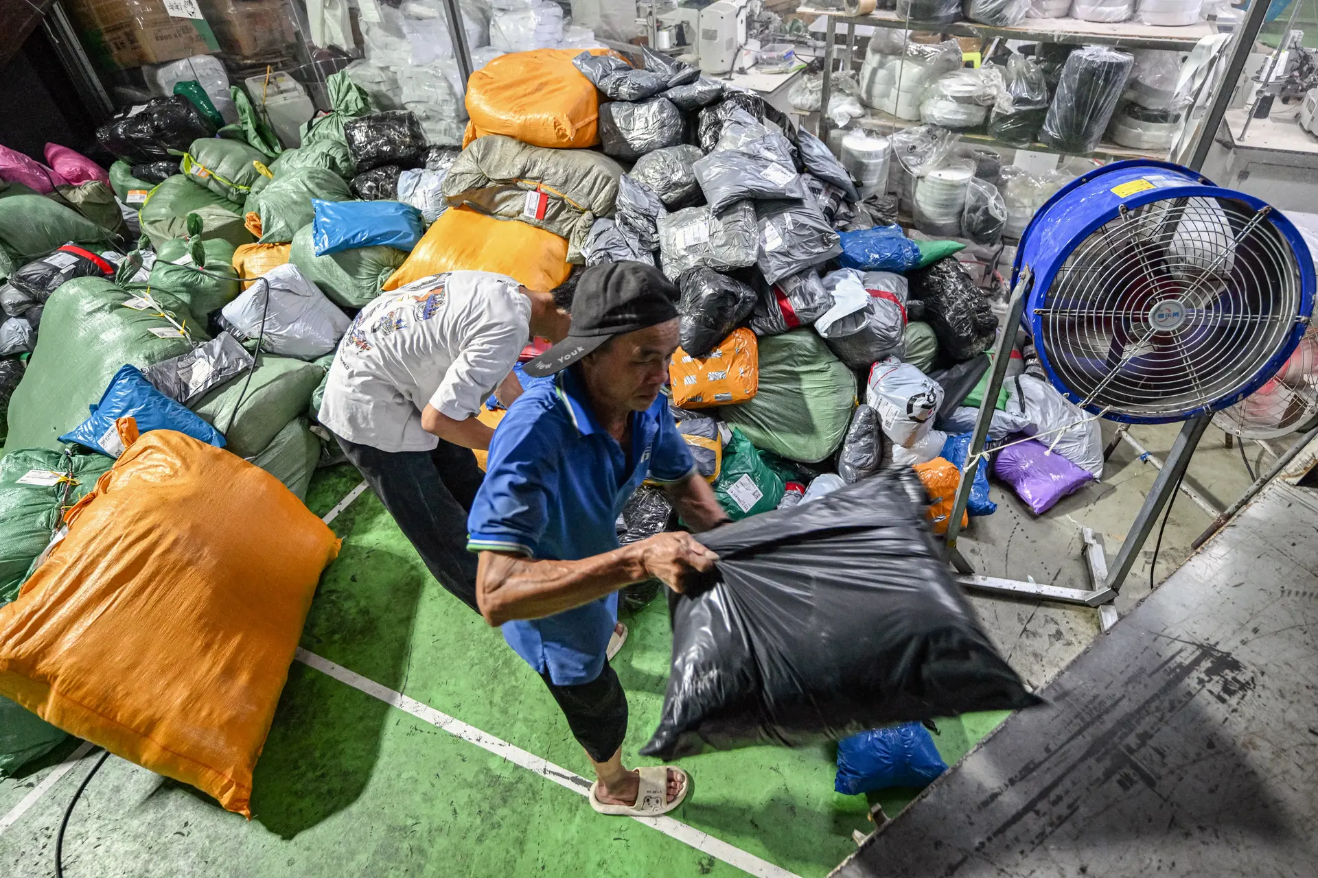 Personas trabajan en un almacén de la empresa de mensajería internacional Weijiang, que gestiona los paquetes del gigante chino del comercio electrónico Temu, en Guangzhou, provincia de Guangdong (China), el 12 de agosto de 2025. (Adek Berry/AFP a través de Getty Images).
