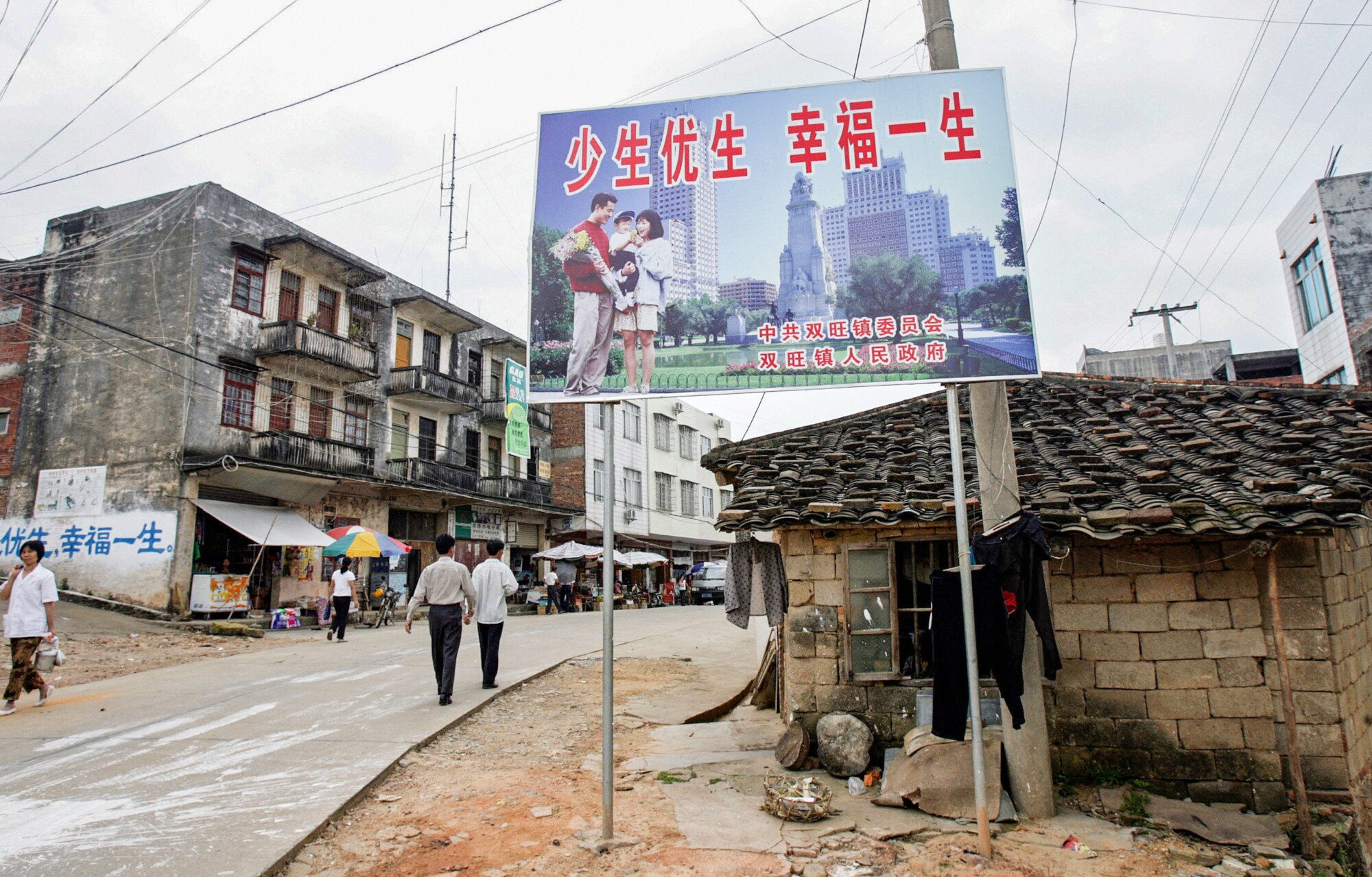 Una valla publicitaria sobre la política del hijo único con el lema «Ten menos hijos, vive mejor» da la bienvenida a los residentes en la calle principal de Shuangwang, provincia de Guangxi, China, en mayo de 2017. (Goh Chai Hin/AFP a través de Getty Images).
