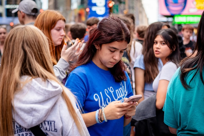 Una joven utiliza un teléfono móvil en la ciudad de Nueva York, el 10 de junio de 2024. Los expertos advierten que la avalancha de imágenes violentas en las redes sociales está distorsionando la actitud de las personas hacia la violencia. (Samira Bouaou/The Epoch Times)