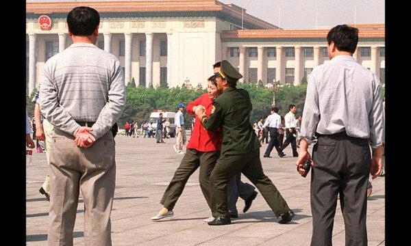 Un practicante de Falun Gong es llevado a la fuerza por la policía china hacia una camioneta policial en la plaza de Tiananmen, en Beijing, el 11 de mayo de 2000. (Stephen Shaver/AFP vía Getty Images)