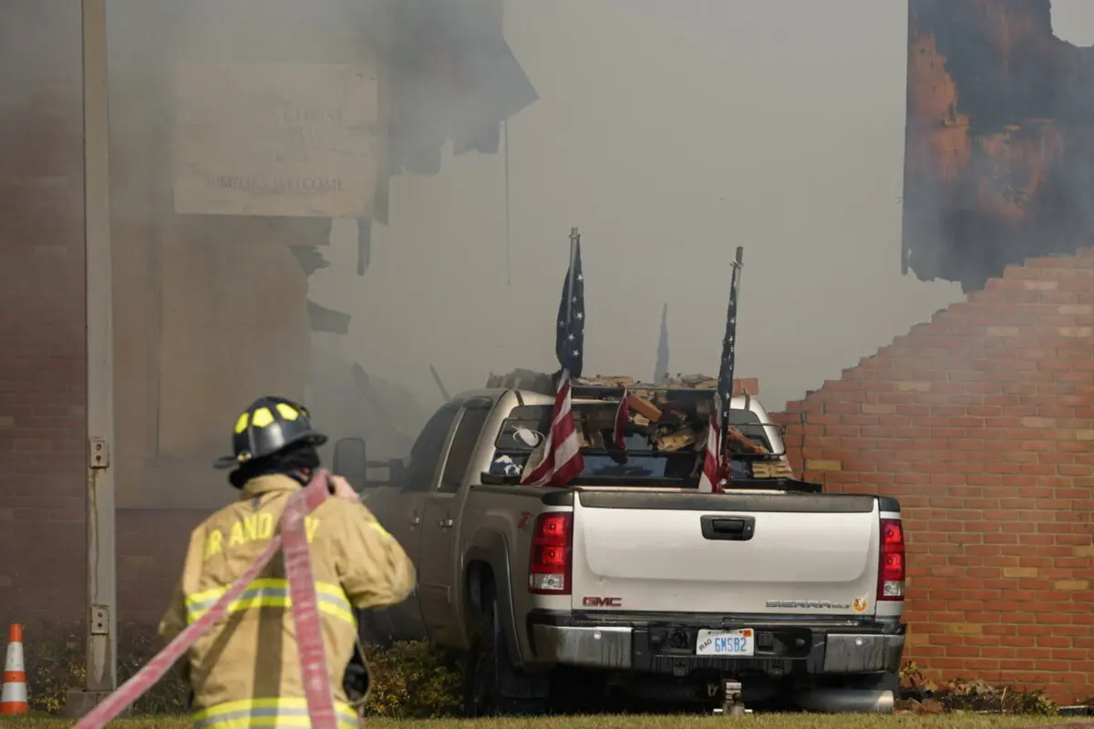 Un vehículo que se estrelló contra el edificio está rodeado de humo mientras un bombero trabaja en el lugar de los hechos en la Iglesia de Jesucristo de los Santos de los Últimos Días en Grand Blanc, Míchigan, el 28 de septiembre de 2025. (Lukas Katilius/The Flint Journal vía AP)