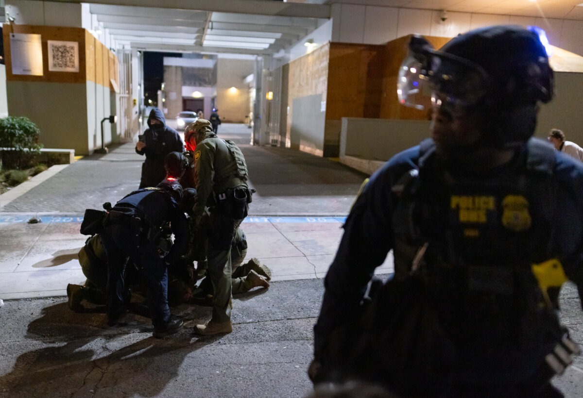 Un hombre es detenido por agentes federales frente a las oficinas del Servicio de Inmigración y Control de Aduanas en Portland, Oregón, el 5 de octubre de 2025. (John Fredricks/The Epoch Times).